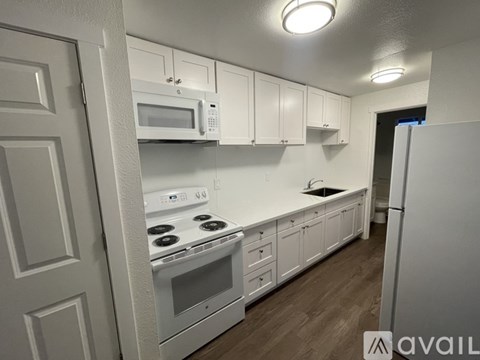 A kitchen with white cabinets and appliances.