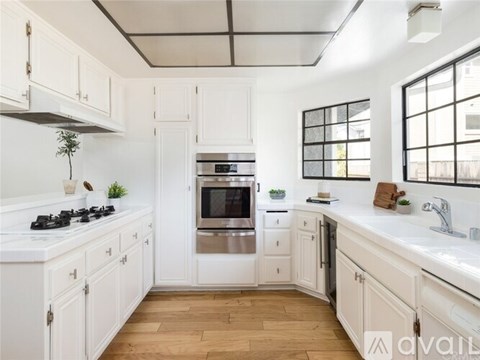 A kitchen with white cabinets and a wooden floor.
