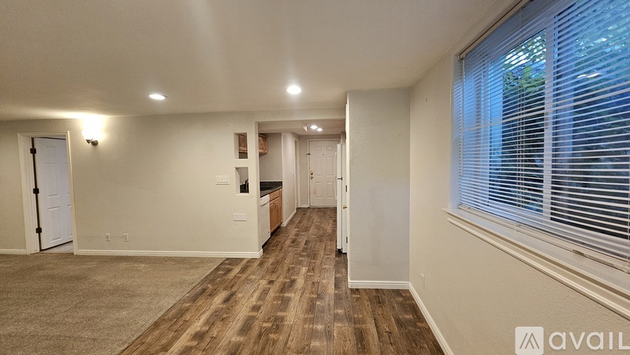 A spacious room with wooden flooring and white walls.