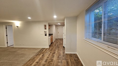 A spacious room with wooden flooring and white walls.