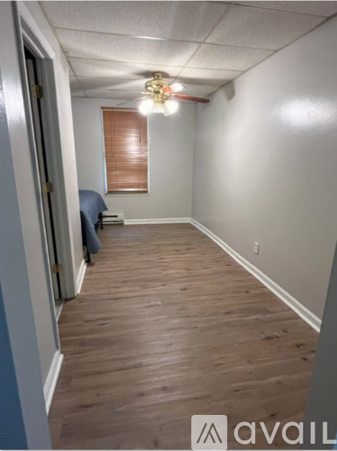 A bedroom with a bed, window with blinds, and a window air conditioner.