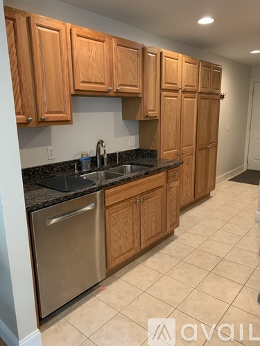 A kitchen with wooden cabinets and a stainless steel dishwasher.