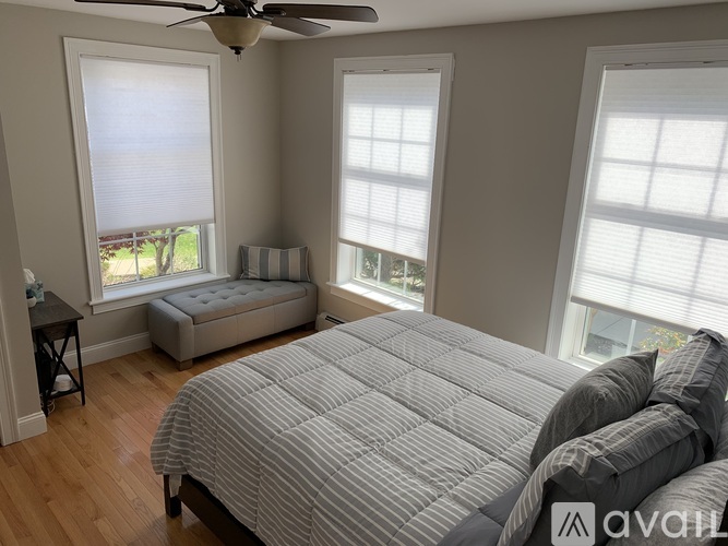 A bedroom with a large bed and a window with blinds.