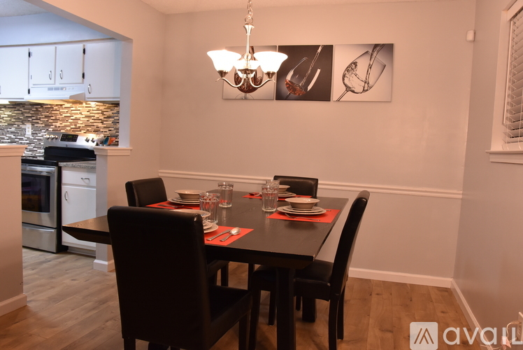 A dining room with a table set for two and a kitchen area in the background.