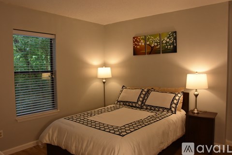 A bedroom with a large bed and two lamps.