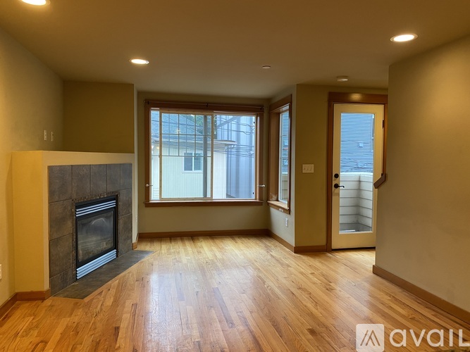 A spacious room with a fireplace and wooden floors.