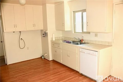 A kitchen with white cabinets and a wooden floor.