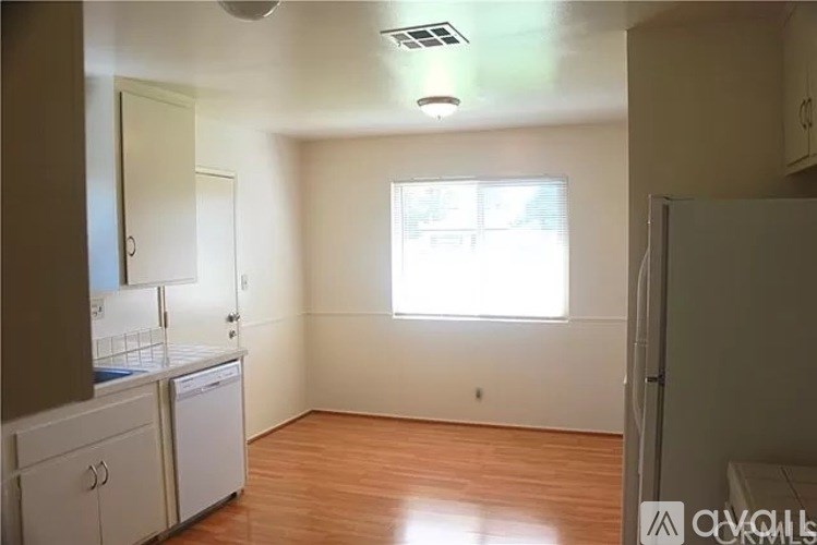 A kitchen with white cabinets and a window.
