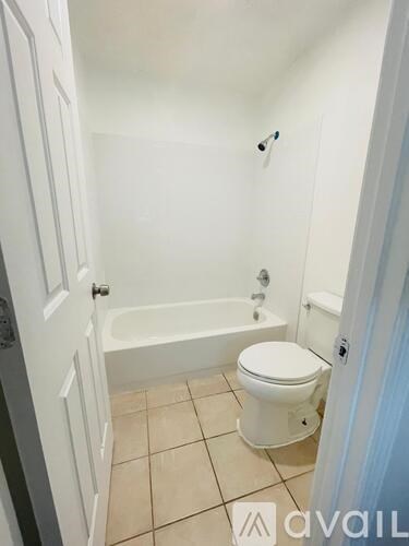 A white toilet sits in a bathroom next to a bathtub.