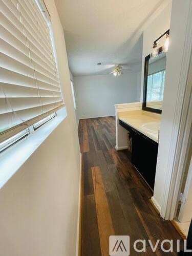 A hallway with wooden floors and white walls.
