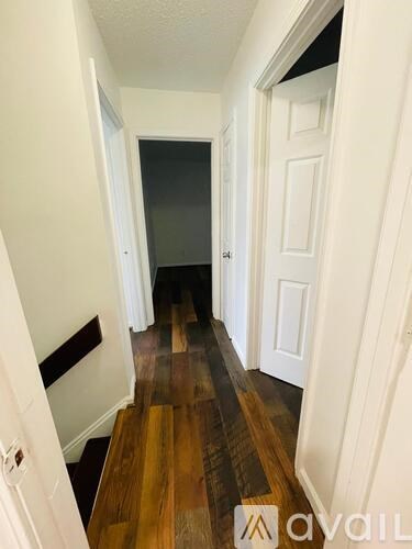 A hallway with wood floors and white walls.