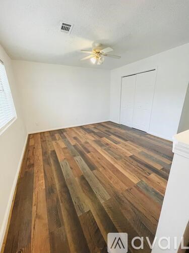 A room with wooden flooring and a ceiling fan.