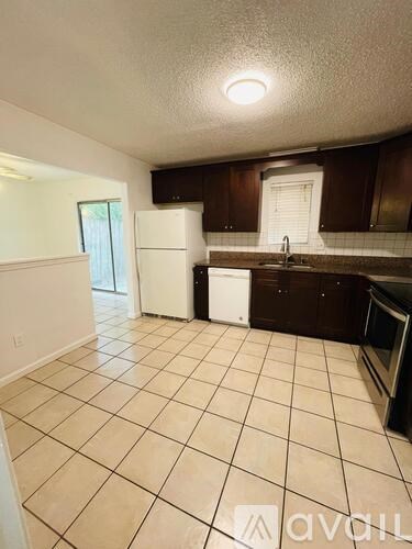 A kitchen with white appliances and brown cabinets.