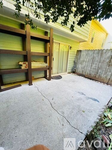 A yellow house with a wooden bunk bed in the backyard.
