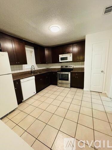 A kitchen with white appliances and brown cabinets.