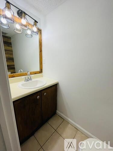 A bathroom with a sink, mirror, and wooden cabinets.