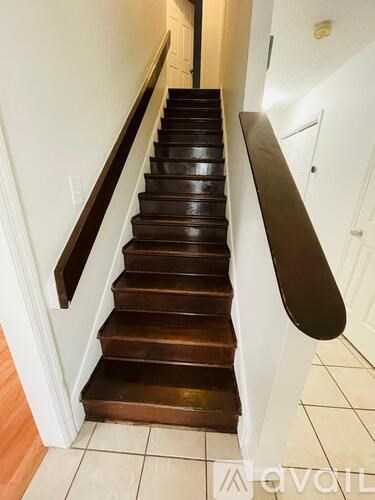 A staircase with a wooden handrail and white walls.