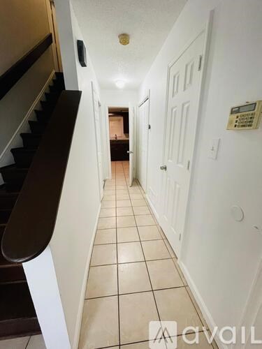 A hallway with a staircase on the left and a door on the right.