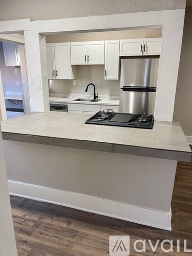 A kitchen with white cabinets and a stove top oven.