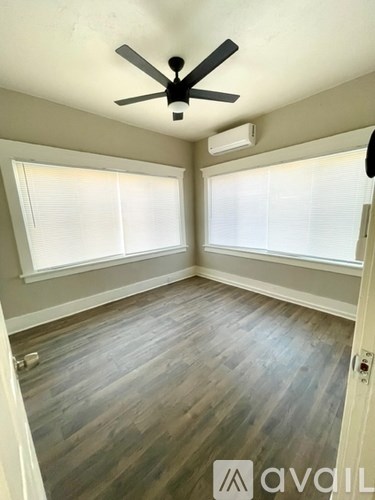 A room with a ceiling fan and two windows.