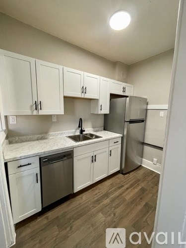 A kitchen with white cabinets and a wooden floor.