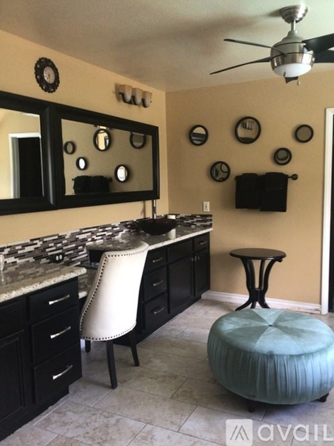 A kitchen with a white chair and a round ottoman.