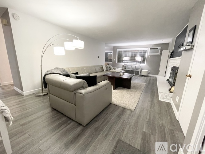 A living room with a grey couch and a white lamp.