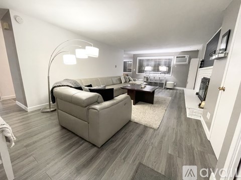 A living room with a grey couch and a white lamp.