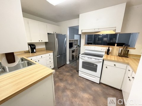 A kitchen with white cabinets and a wooden countertop.