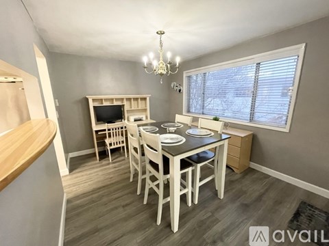 A dining area with a table set for four and a chandelier hanging from the ceiling.