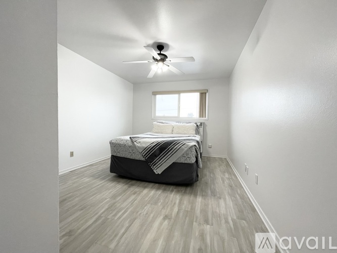 A bedroom with a bed, a window, and a ceiling fan.