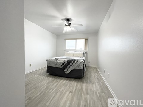 A bedroom with a bed, a window, and a ceiling fan.