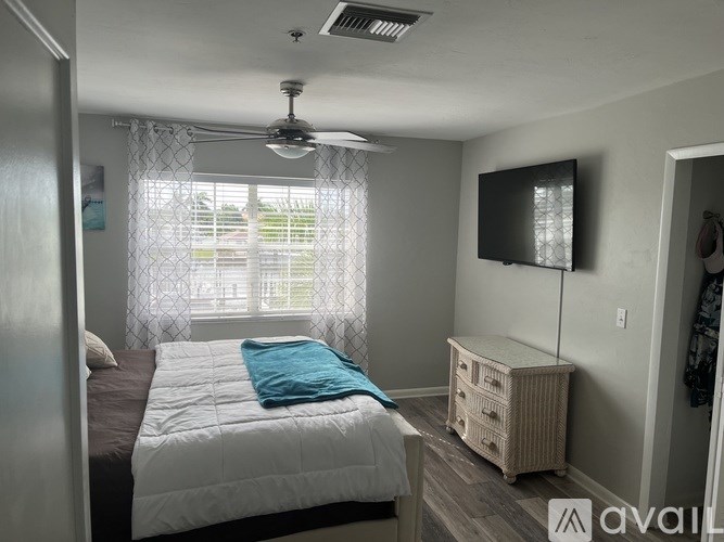 A bedroom with a bed, a ceiling fan, and a television.