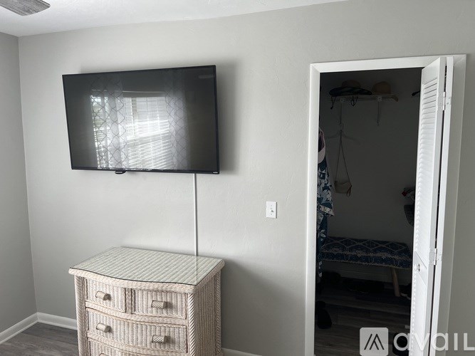 A television is mounted on a wall above a cabinet with drawers.