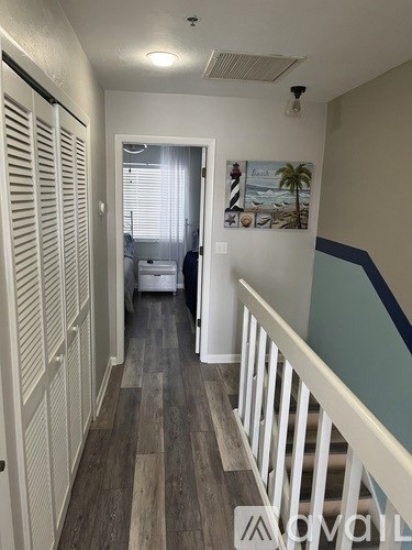 A hallway with a white railing and wooden floors.