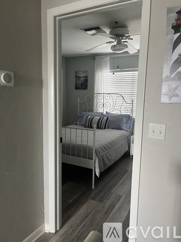 A bedroom with a bed, a ceiling fan, and a mirror.