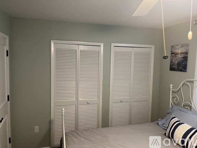 A bedroom with a bed, two closets, and a ceiling fan.