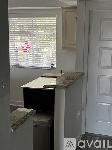 A small kitchen with a marble counter top and a window with blinds.