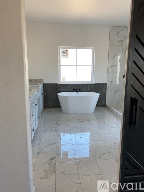 A bathroom with a white tub and marble flooring.