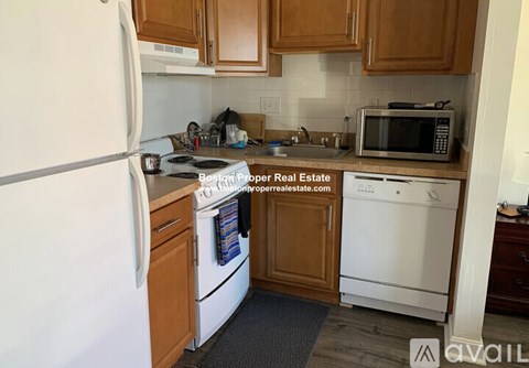 A kitchen with a white refrigerator, white dishwasher, and wooden cabinets.