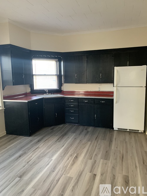 A kitchen with black cabinets and a white refrigerator.