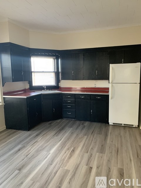 A kitchen with black cabinets and a white refrigerator.
