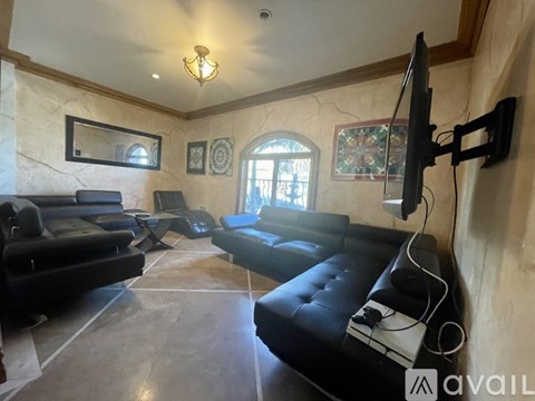 A living room with black leather furniture and a flat screen TV mounted on the wall.