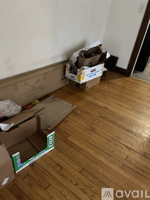 A room with a wooden floor and a cardboard box with a green label on it.