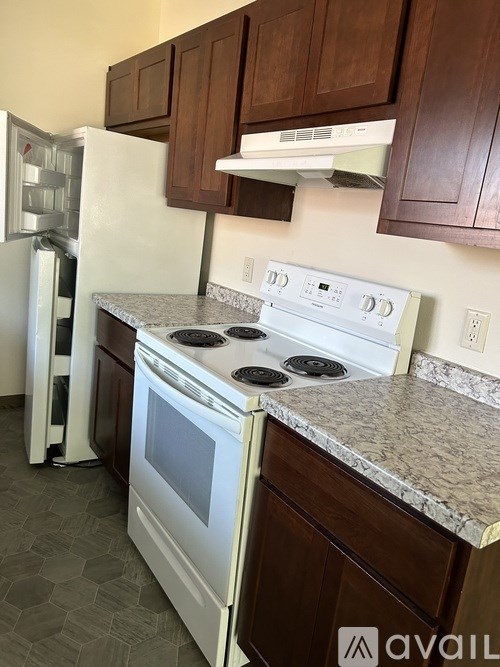 A white stove top oven with a white refrigerator in the background.