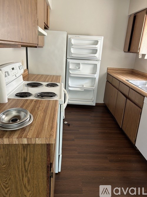 A kitchen with a white stove and a white refrigerator with the door open.