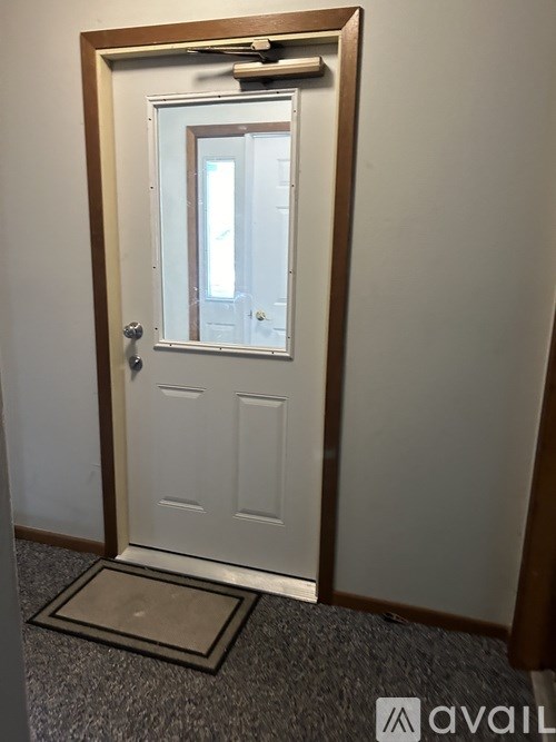 A white door with a mirror above it and a doormat in front.