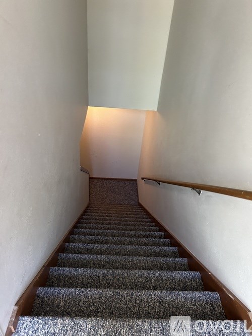 A staircase with a carpeted floor and a light at the top.