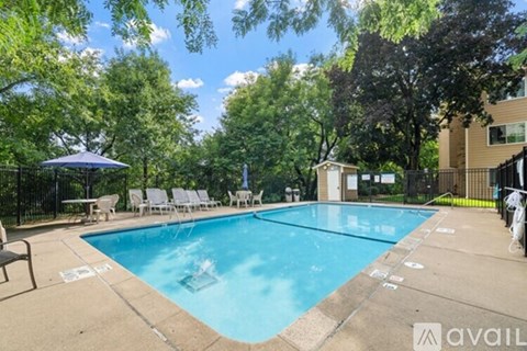 A pool surrounded by trees and chairs.