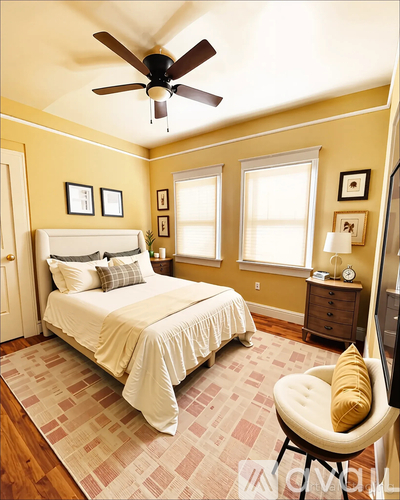 A bedroom with a bed, chair, and ceiling fan.